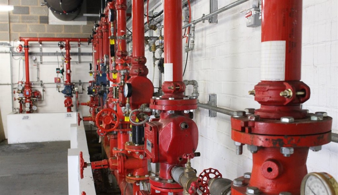 Fire sprinkler riser room with red valves and gauges